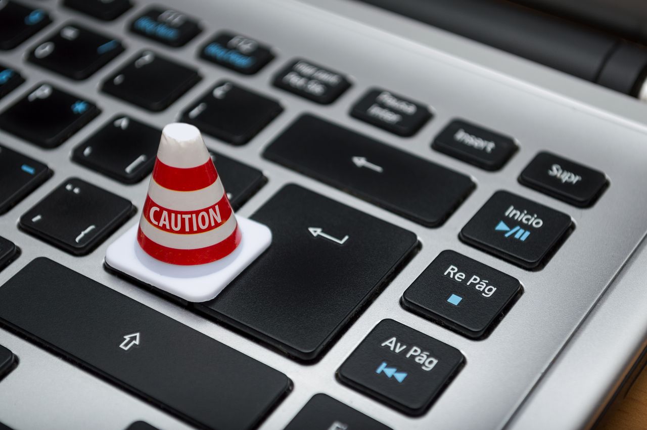 Home Miniature caution cone on a computer keyboard symbolizing data security and control.